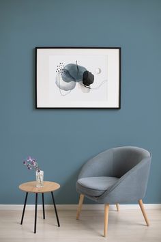 a chair and table in front of a blue wall with a painting on the wall