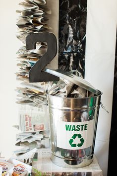 a trash can sitting on top of a pile of papers next to a metal number 2