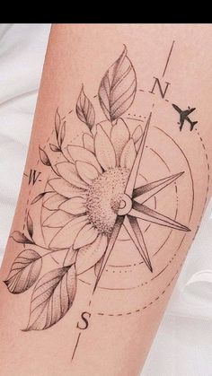 a sunflower tattoo on the arm with an airplane in the sky above it and a compass