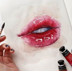 a person is holding a paintbrush and painting a watercolor drawing of a woman's lips