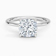 a cushion cut diamond ring on a white background with the center stone in the middle