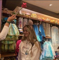 a woman in a store looking at items on shelves and holding a pair of scissors