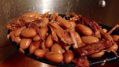 some beans and bacon are in a black bowl