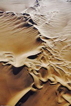 an aerial view of sand dunes in the desert, with ripples and patterns on them