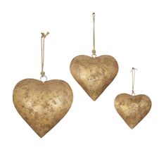 three gold heart shaped ornaments hanging from strings