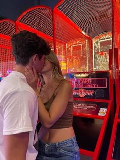 a man and woman kissing in front of an arcade machine