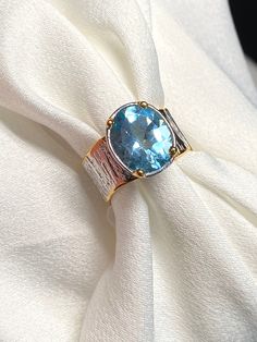 Blue Topaz Ring with gold accents size 7  Materials: Silver 925 rhodium plated, 22K Gold plated, Blue Topaz Face of the ring: Height - 12mm, width-10mm, band-10mm Rhodium plated means jewelry made from a base metal of gold, silver, or other alloy that is coated in a thin layer of rhodium for extra strength and luster. Jewelry plated in rhodium is shinier and more durable than other metals. Rhodium plating does not scratch, dent, or corrode and retains its luster Please note: Colors may vary slig Unisex Ring, Blue Band, Ring Gemstone, Blue Topaz Ring, Topaz Ring, 22k Gold, Jewelry Plate, Base Metal, Gemstone Ring