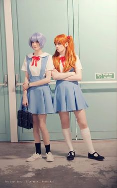 two women dressed in blue and white standing next to each other with their arms crossed