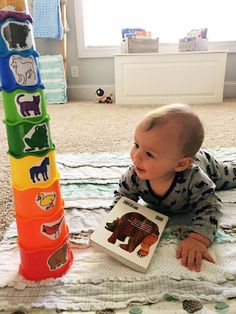 a baby laying on the floor next to a stack of books with animals on them