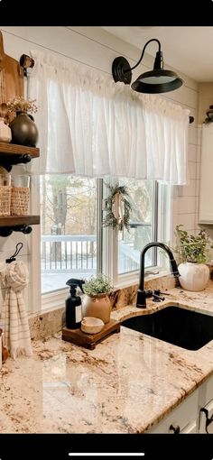 a kitchen with white cabinets and marble counter tops, black faucet, open shelves above the sink