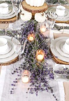 the table is set with white plates, silverware and lavender sprigs in glass vases