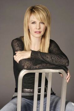 a woman sitting on top of a chair with her arms crossed and looking at the camera