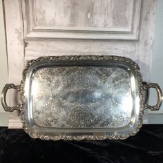 an ornate silver tray sitting on top of a black cloth covered floor next to a white door