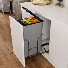 a trash can is open in the middle of a kitchen with white cabinets and drawers