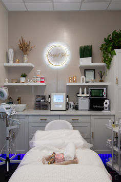 This Esthetician salon studio in Huntington Beach, California has a white theme with a unique lighting fixture to create a clean, warm feel. Spa Room Sinks, Esthetician Room Shelves, Boho Western Esthetician Room, Esthetician And Nail Room, Wax Area In Salon, Esthetician Room Lighting Ideas, Esthetician Room Cabinets, Girly Esthetician Room, Beauty Salon At Home Ideas