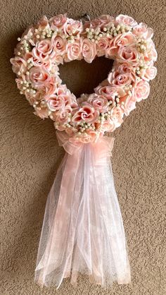 a heart shaped wreath with pink roses on it