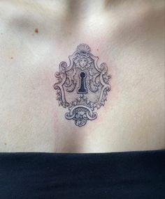 a woman's chest with a lock and keyhole tattoo on her left side