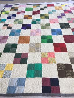 a multicolored patchwork quilt is displayed on a bed sheet that has been made into a blanket