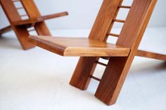 two wooden chairs sitting next to each other on a white floor in front of a wall