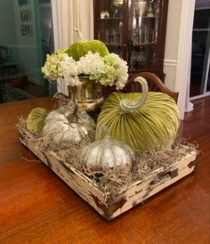 a wooden table topped with green velvet pumpkins and other decorative items on top of it