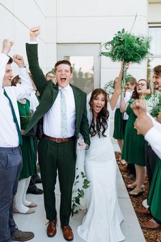 a bride and groom are surrounded by their wedding party as they walk down the aisle