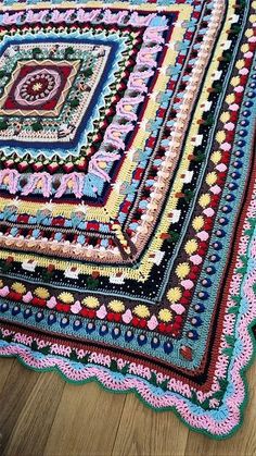 a crocheted afghan is laying on the floor in front of a wooden floor