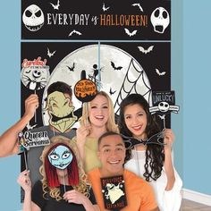 a group of people standing next to each other in front of a halloween sign with faces on it