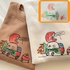 two children's t - shirts with cars drawn on them, one is brown and the other is white