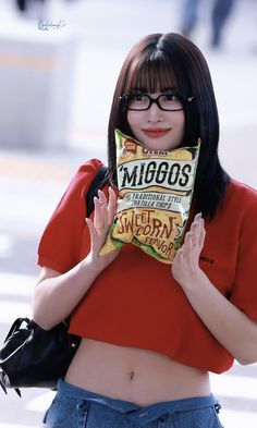 a woman with glasses holding up a bag of chips