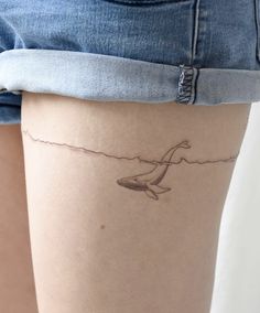 a woman's thigh with a whale tattoo on it