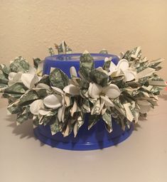 a blue bowl filled with money sitting on top of a white table next to a wall