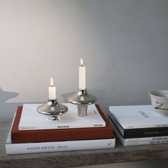 two candles sitting on top of books next to each other