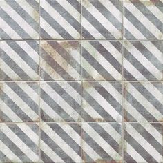 an old tile wall with diagonal stripes in grey and white