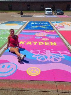 a woman sitting on the ground in front of a painted walkway