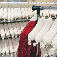 several pieces of clothing hanging on a rack in front of other white ones and hangers