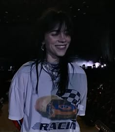 a woman with long black hair wearing a white shirt and holding a skateboard in her hand