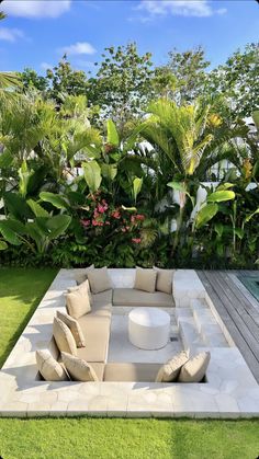 an outdoor living area with couches, tables and tropical trees in the back yard