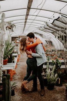 a man and woman embracing in a greenhouse