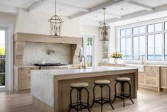 a large kitchen with an island and three stools in front of the counter top