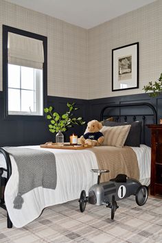 a teddy bear sitting on top of a bed next to a dresser and window in a bedroom