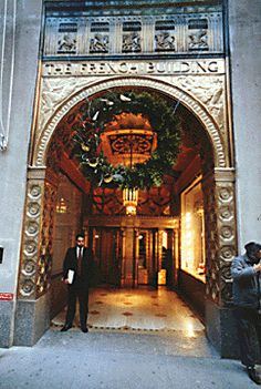 two men standing in front of an entrance to a building with a wreath on the door