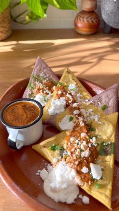 three quesadillas on a plate with salsa and sour cream in the middle