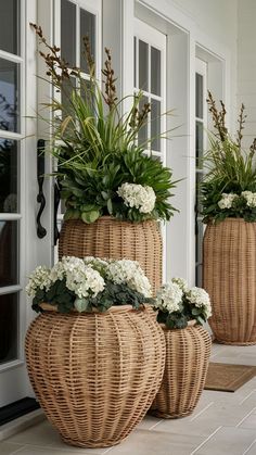 three wicker planters with white flowers in them on the front step of a house