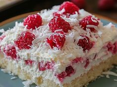 a piece of cake with white frosting and raspberries on top