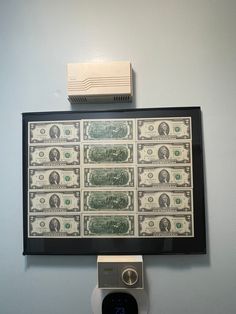 an electronic device mounted to the side of a wall next to a money bill and air conditioner