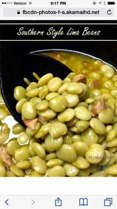 a spoon full of green beans sitting on top of a white tablecloth with the words southern style lima beans