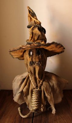 an old scarecrow doll wearing a hat and holding a rope in its mouth on a wooden floor