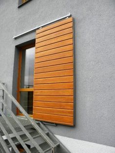 an open window on the side of a building with stairs leading up to it's door