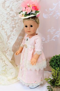 a doll with a pink dress and flower crown on her head is standing next to a potted plant