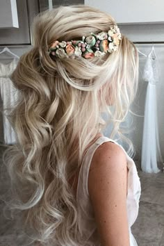 a woman with long blonde hair wearing a flowered headpiece in front of her wedding dress